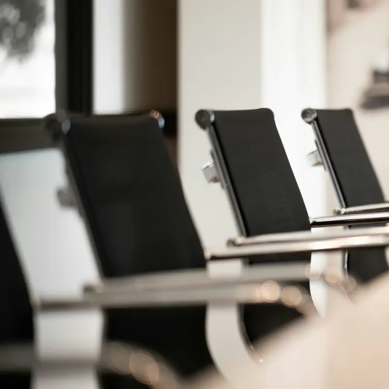 Empty black meeting-room chairs at a boardroom table